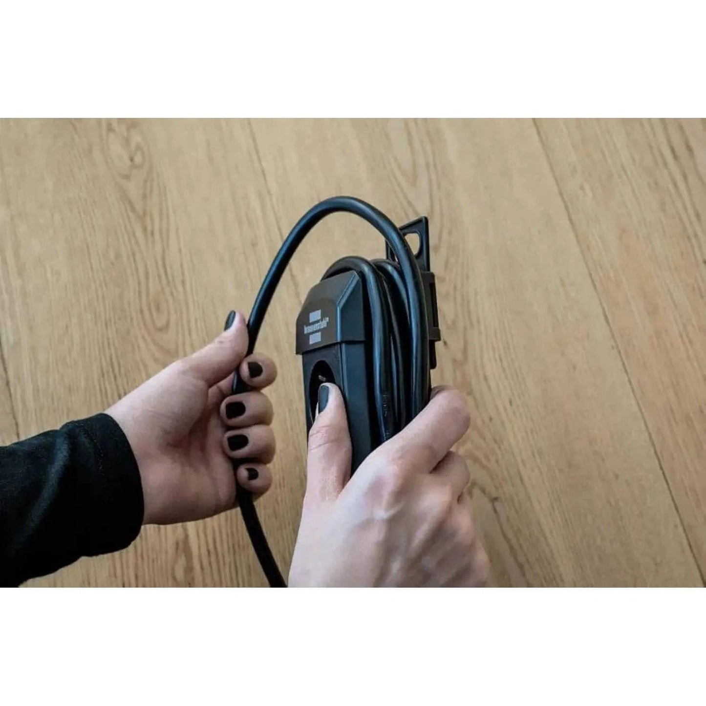 Brennenstuhl Premium Line Multistandard 5-way extension cord, 3m, black/grey, held by hands on a wooden floor