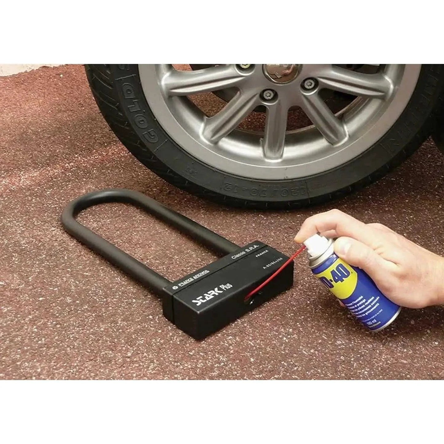 WD-40 Original Rust Remover 330ml spray can beside a black rust-remover device with curved handle near a car wheel.