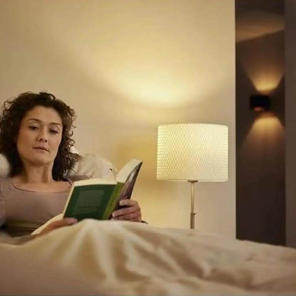 Philips CorePro LEDcapsule G4 2W bulb, warm white (827), bedside lamp scene with a woman reading in bed. UAE