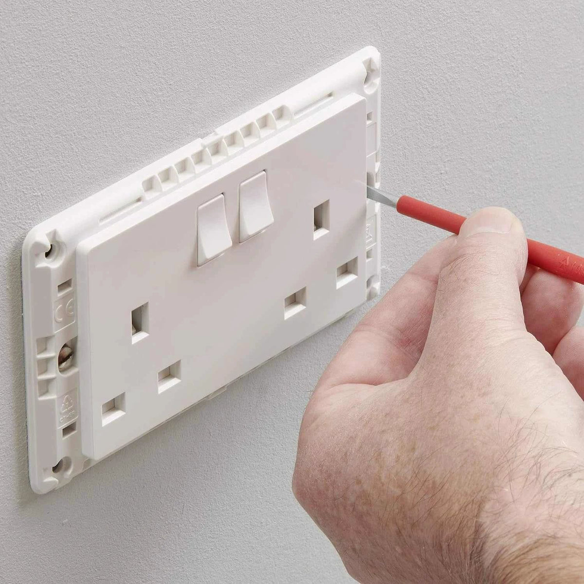 MK Electric MV2747WHI 2G 13A switched socket, white, being installed with screwdriver in hand UAE