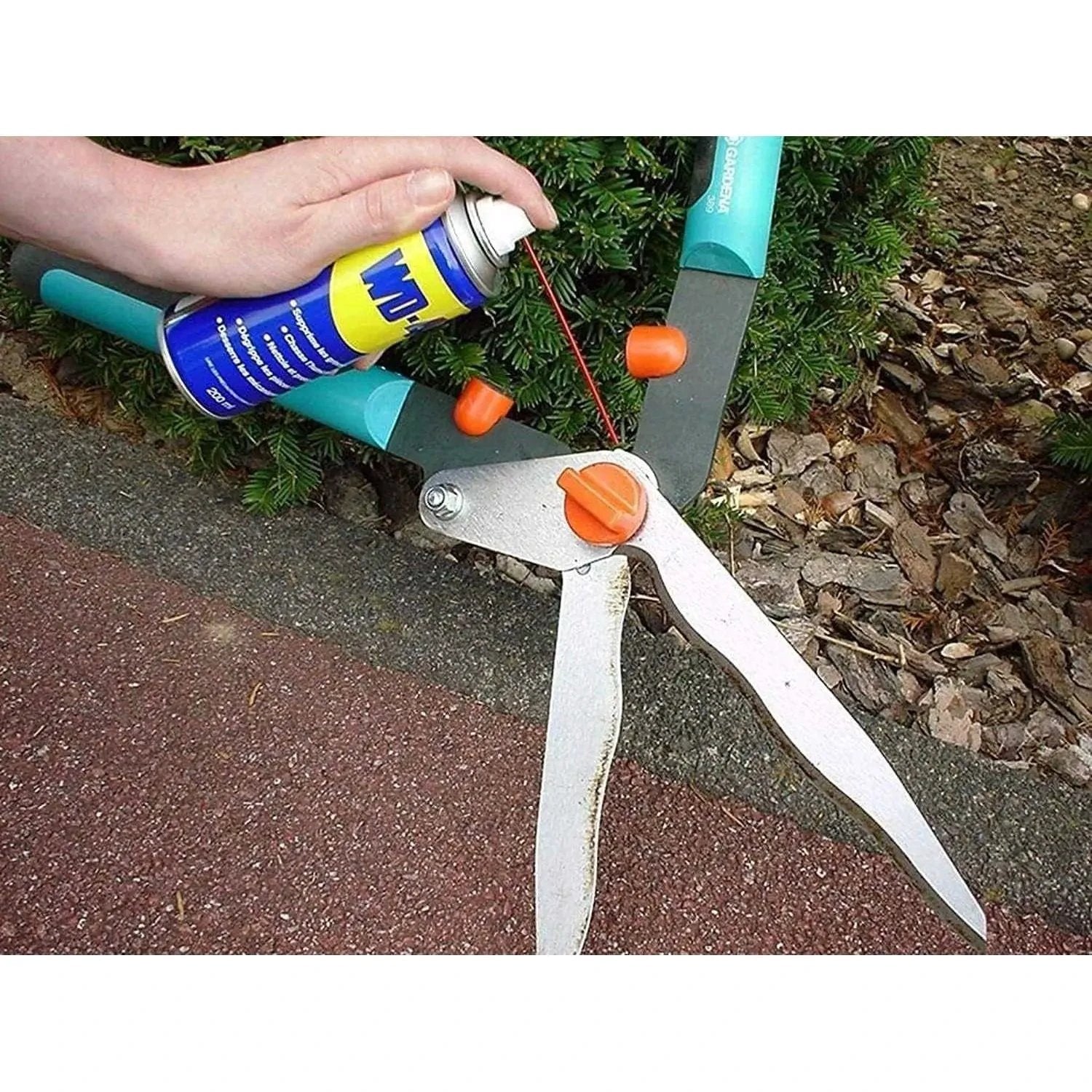 WD-40 Multi-Use Product Original Rust Remover, 330ML being sprayed on a rusted metal tool with orange knobs UAE